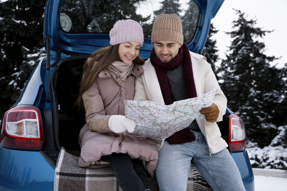 kobieta i mężczyzna trzymająca mapę planują zimą wycieczkę autem